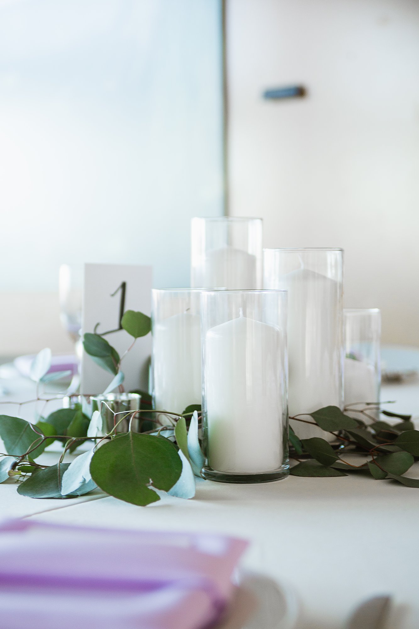 Simple candle, eucalyptus, and wood wedding centerpiece by wedding photographer PMA Photography.