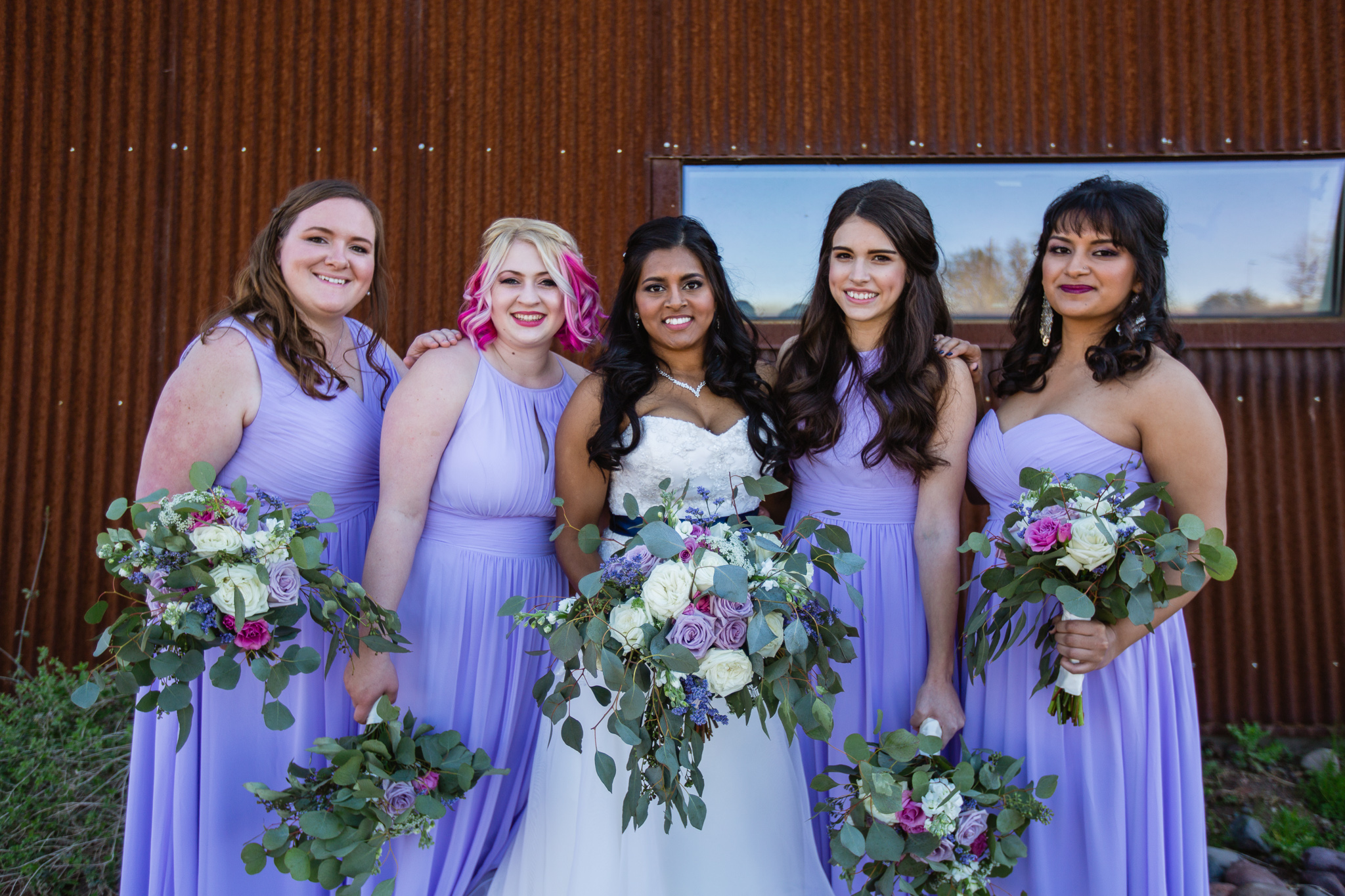 Bride with bridesmaids in lavender dresses with lavender and pink bouquets at the Rio Salado Audubon Center by Phoenix wedding photographers PMA Photography.