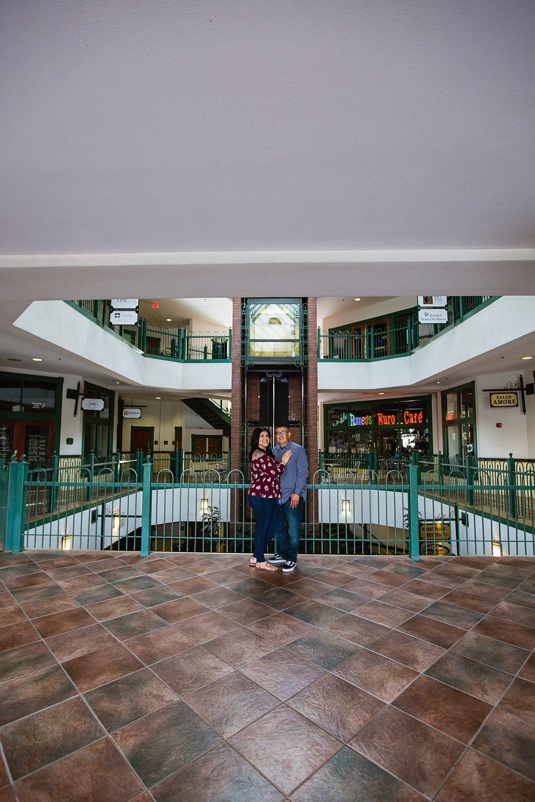 Couple posing in historic shopping center during their Gilbert heritage district engagement session by wedding photographer PMA Photography.