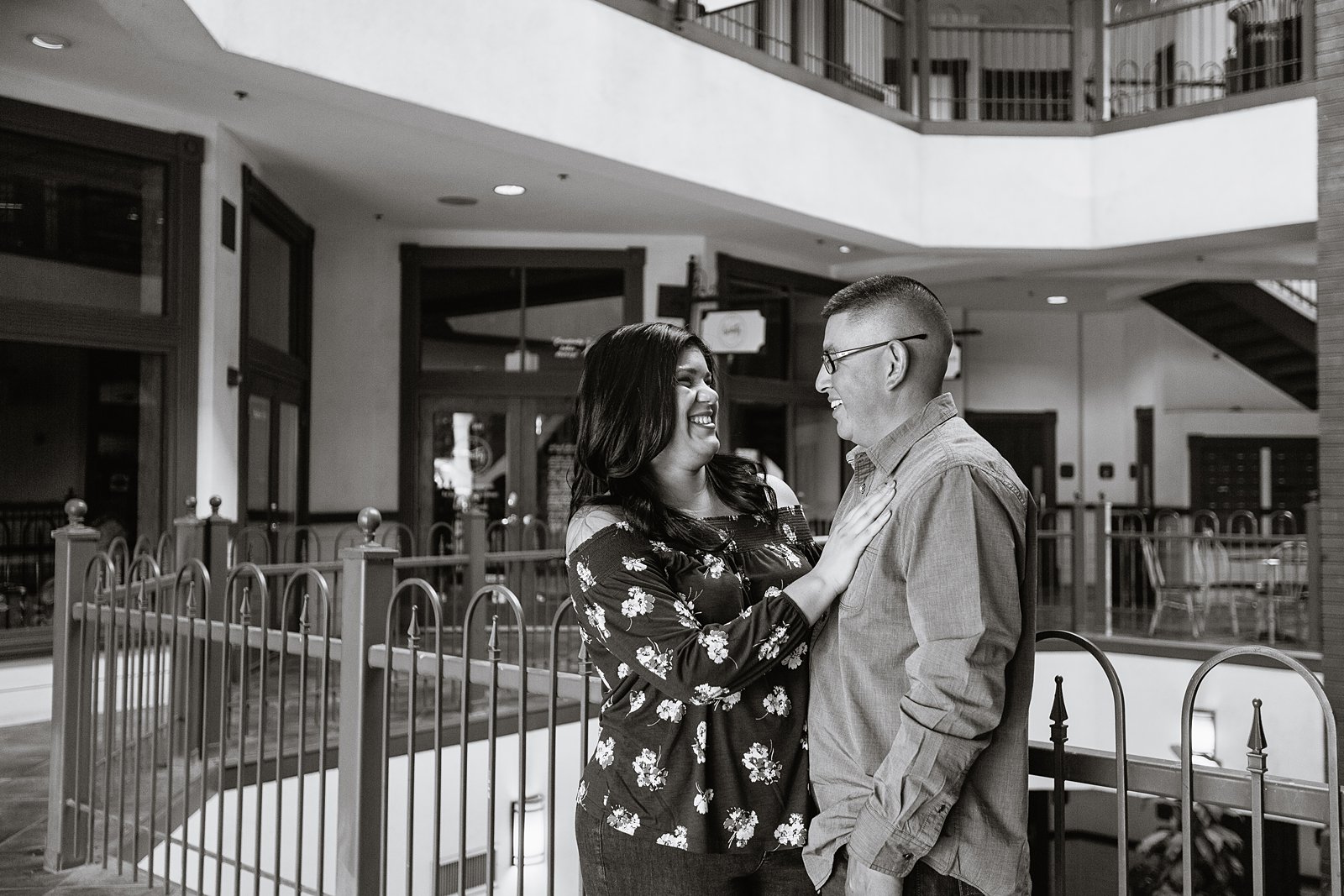 Black and white image of couple sharing a laugh in Gilbert heritage district during their engagement session by PMA Photography.