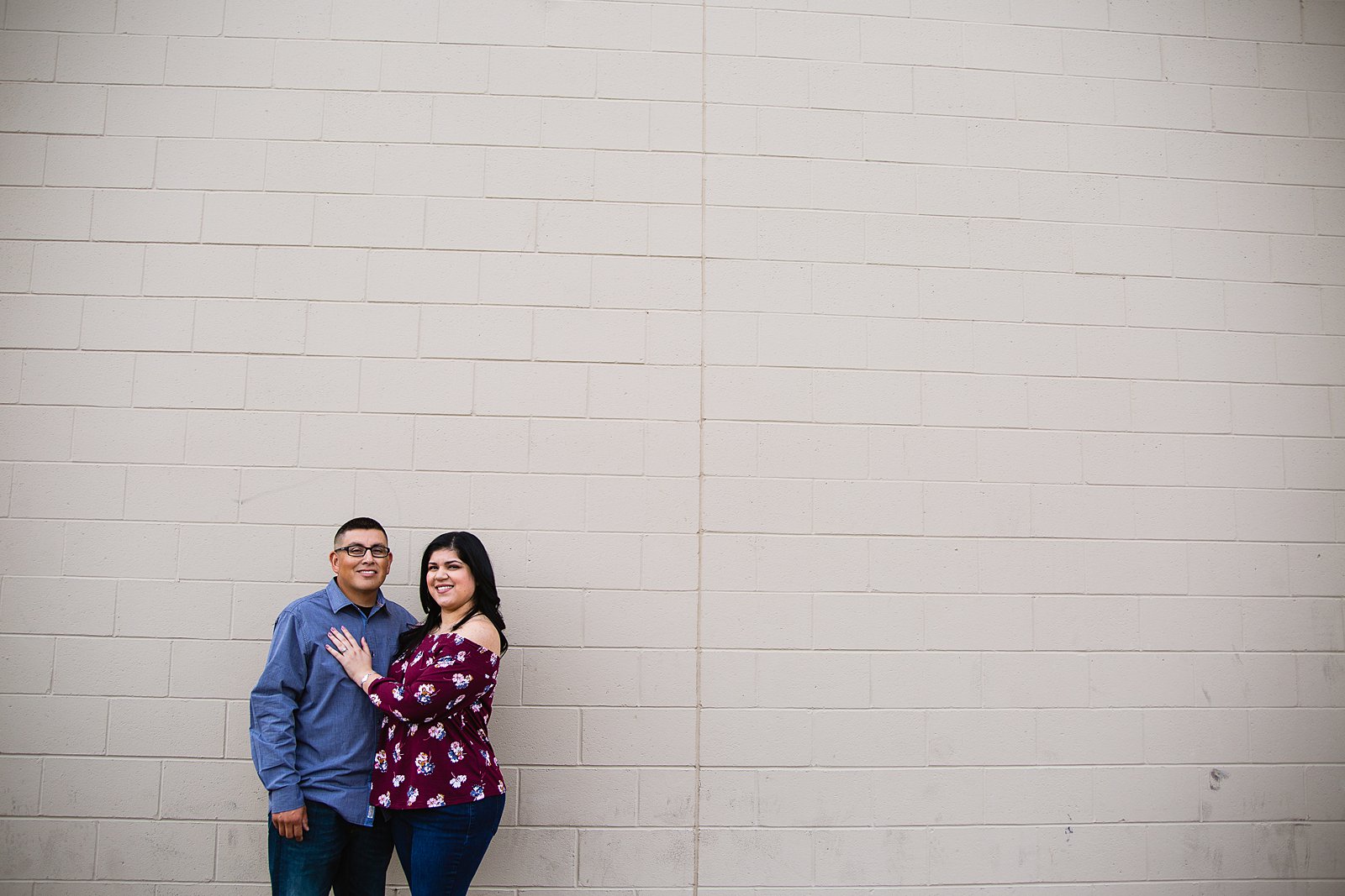 Couple in front of brick wall during their engagement session by Phoenix wedding photographer PMA Photography.
