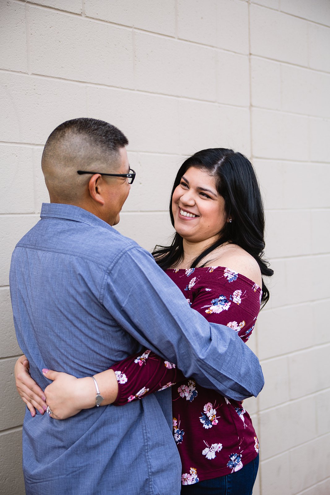 Couple looking at each other against brick wall during their engagement session by Phoenix wedding photographer PMA Photography.