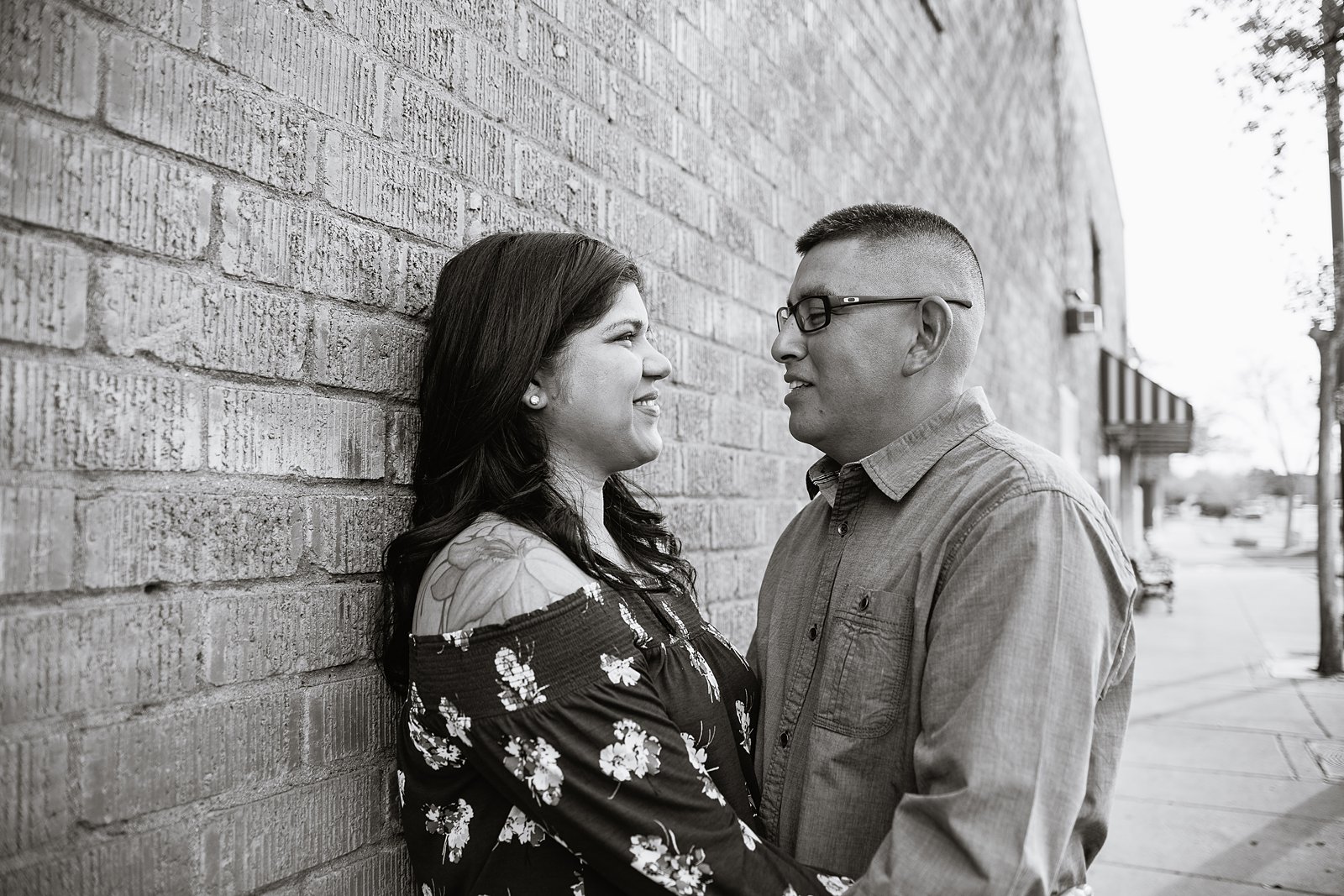 Black and White image of couple against brick wall during their downtown Gilbert engagement session by wedding photographer PMA Photography.