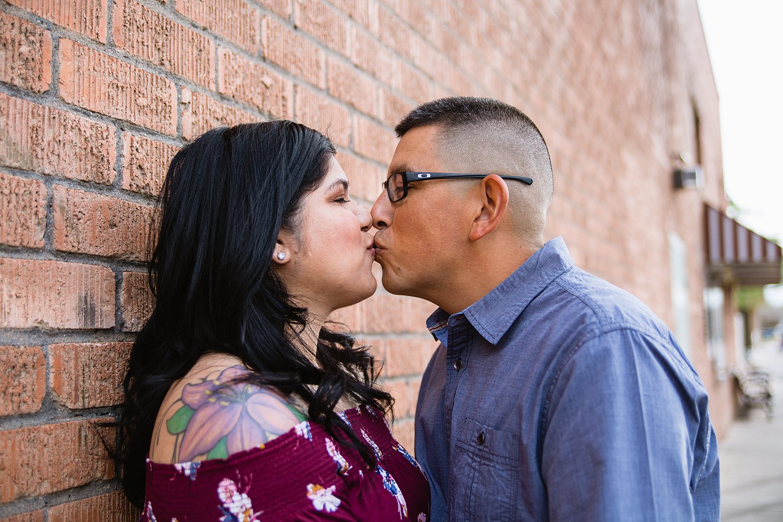 Couple kissing on brick wall during their engagement session.