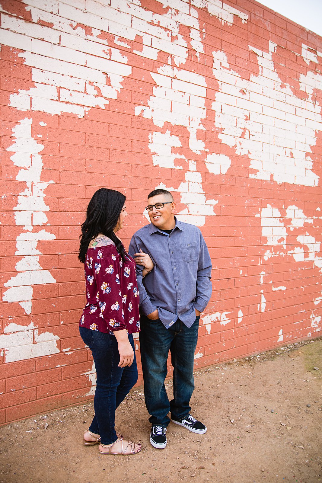 Couple in front of vintage wall with paint chipping off during their Gilbert engagement session by wedding photographer PMA Photography.