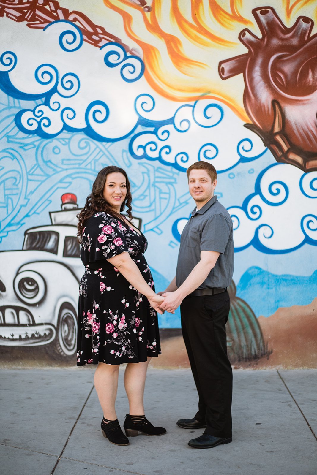 Couple holding hand in front of art mural during their Roosevelt Row Art District engagement session by PMA Photography.