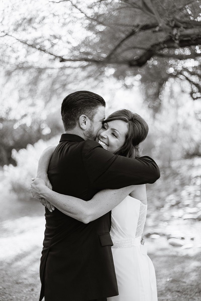 Black and white image of bride and groom embracing each other by Arizona wedding photographer PMA Photography.