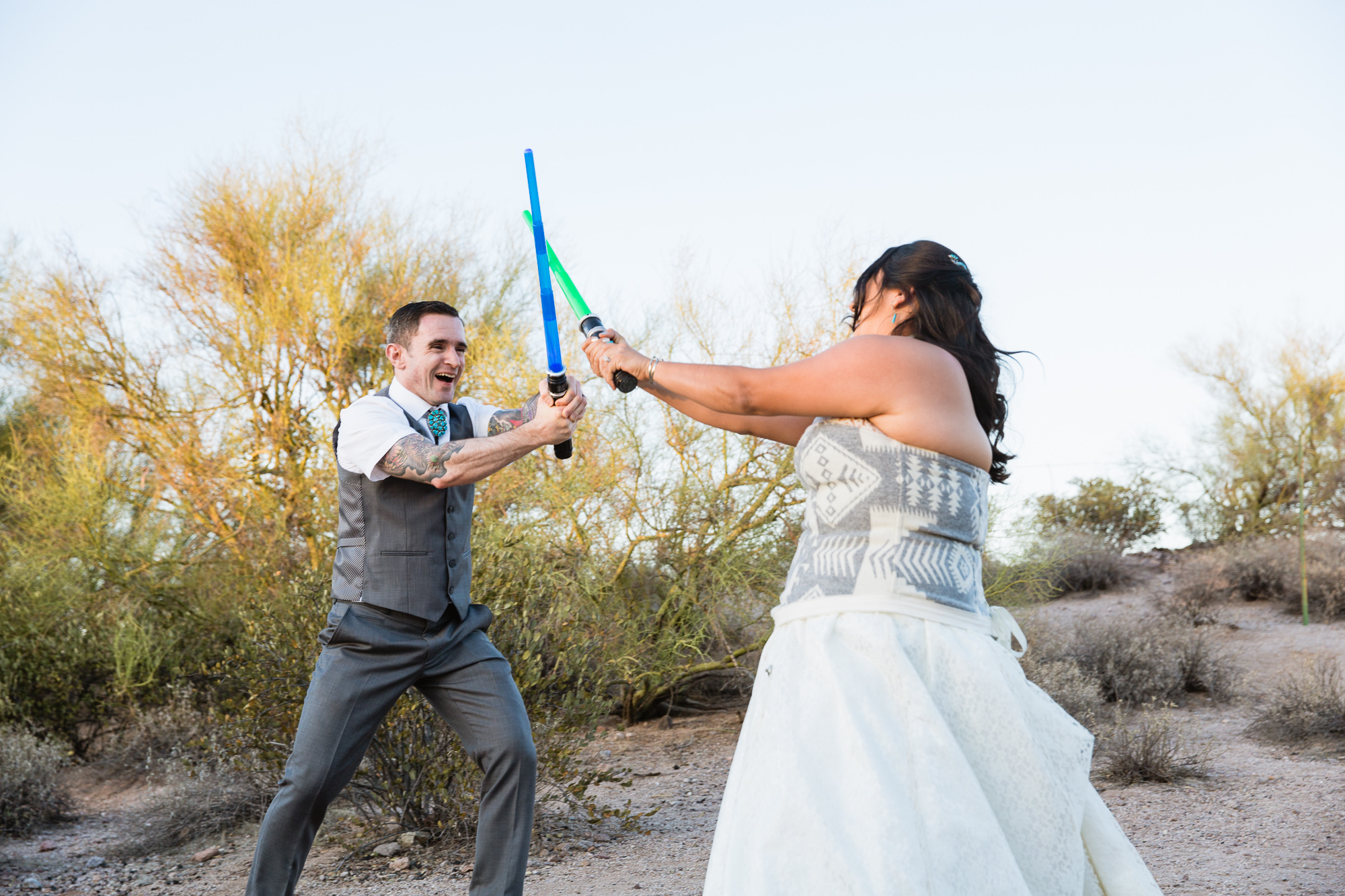Bride and groom in a light saber duel to start their first dance at their Lost Dutchman State Park wedding reception by Arizona wedding photographer PMA Photography.