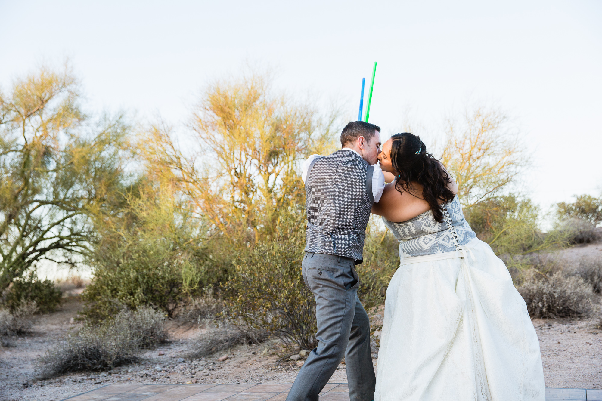 Bride and groom in a light saber duel to start their first dance at their Lost Dutchman State Park wedding reception by Arizona wedding photographer PMA Photography.