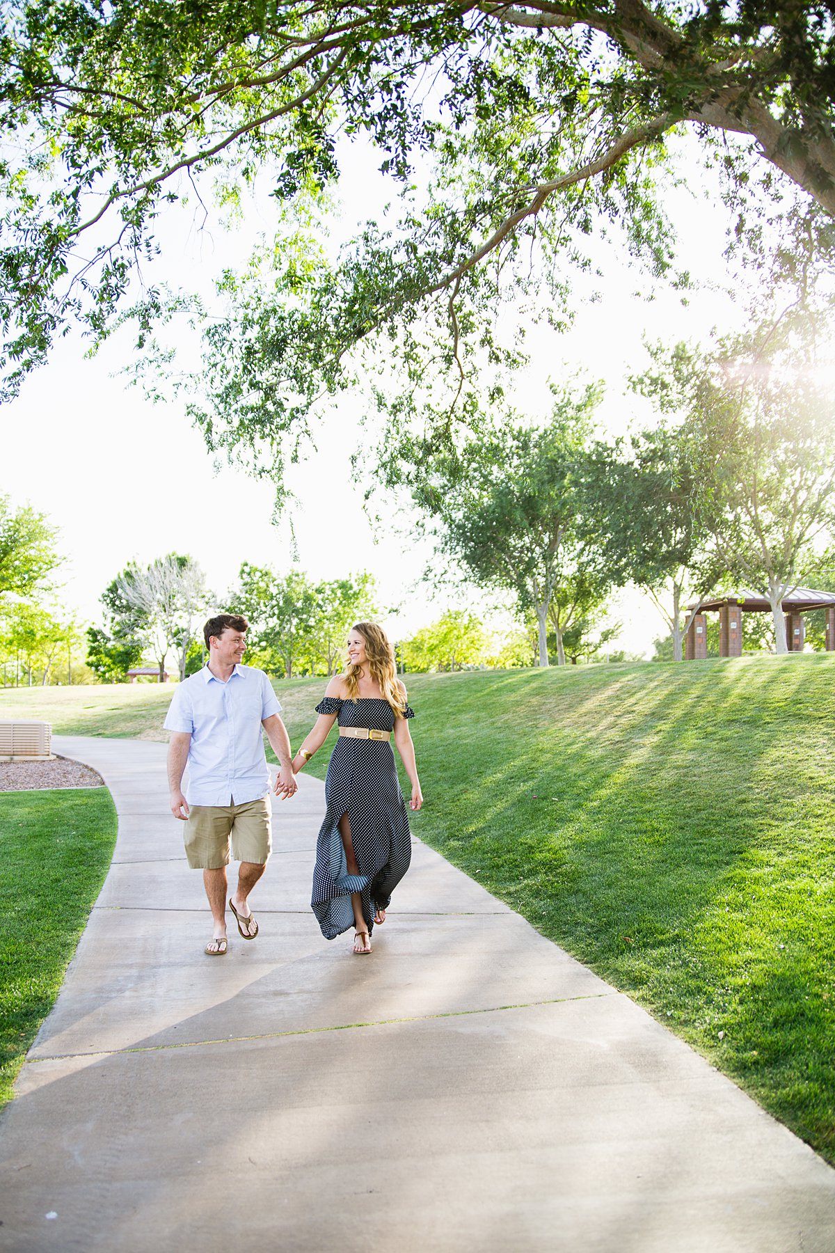 Couple holding hands and walking through Anthem Community Park by engagement photographer PMA Photography.