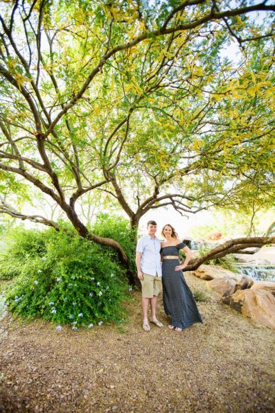 Couple posing during their engagement session in front of blossoming Palo Verde by PMA Photography. 