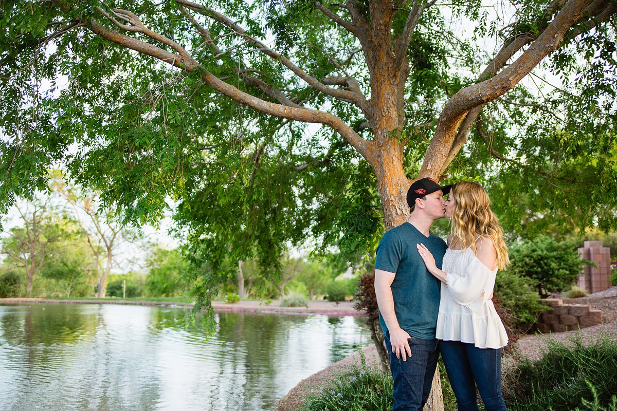Couple posing next to a lake a their Anthem Community Park engagement session by PMA Photography.