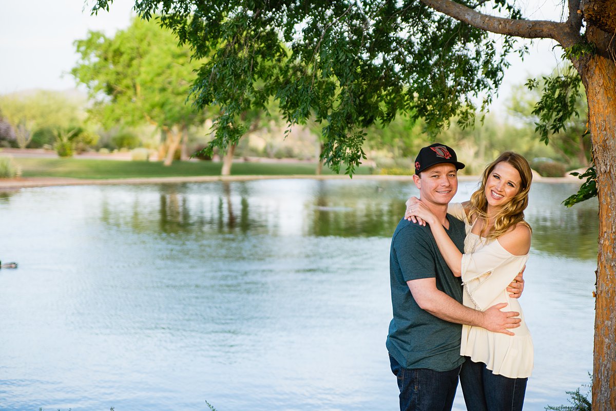 Couple posing next to a lake a their Anthem Community Park engagement session by PMA Photography.
