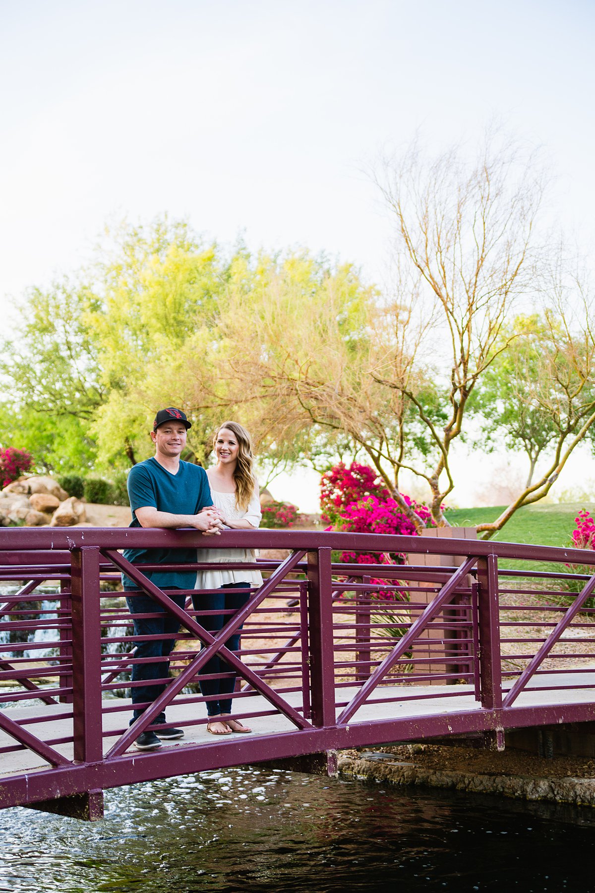 Couple posing on a bridge at Anthem Park in front of their engagement session by PMA Photography.