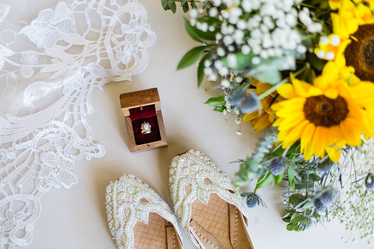 Bridal details of lace, beaded flats, sunflower bouquet, and rose gold and opal ring by PMA Photography.