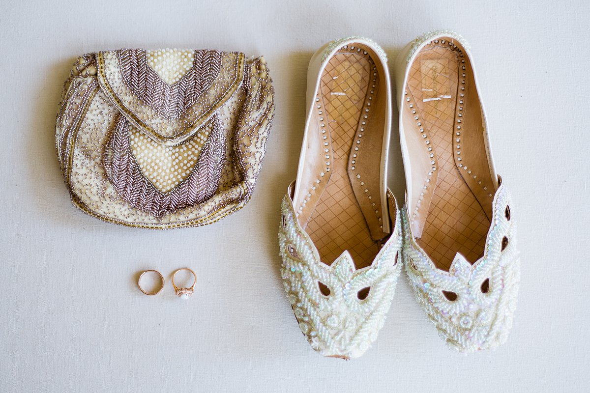 Beaded bridal flats and purse with her rose gold wedding rings by PMA Photography.