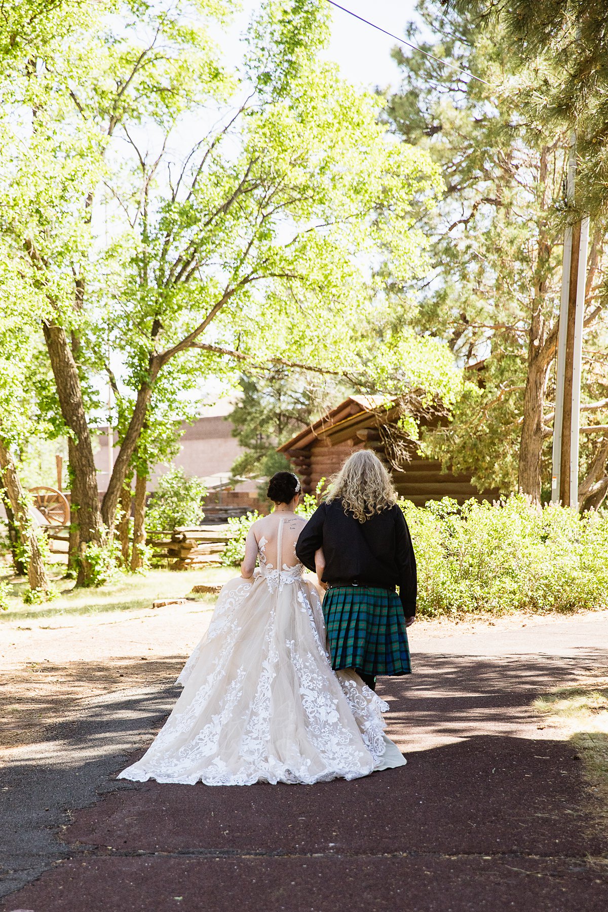 Bride and groom walk together in the woods at the Riordan Mansion at their Scottish and Sunflower inspired wedding by Flagstaff wedding photographers PMA Photography.