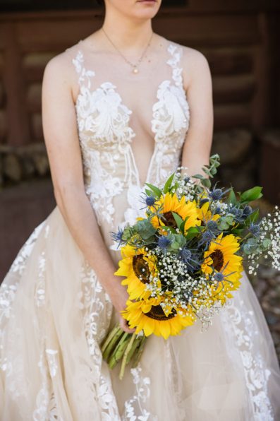 Detail image of a brides nude and lace wedding dress with sunflower bouquet by wedding photographer PMA Photography.