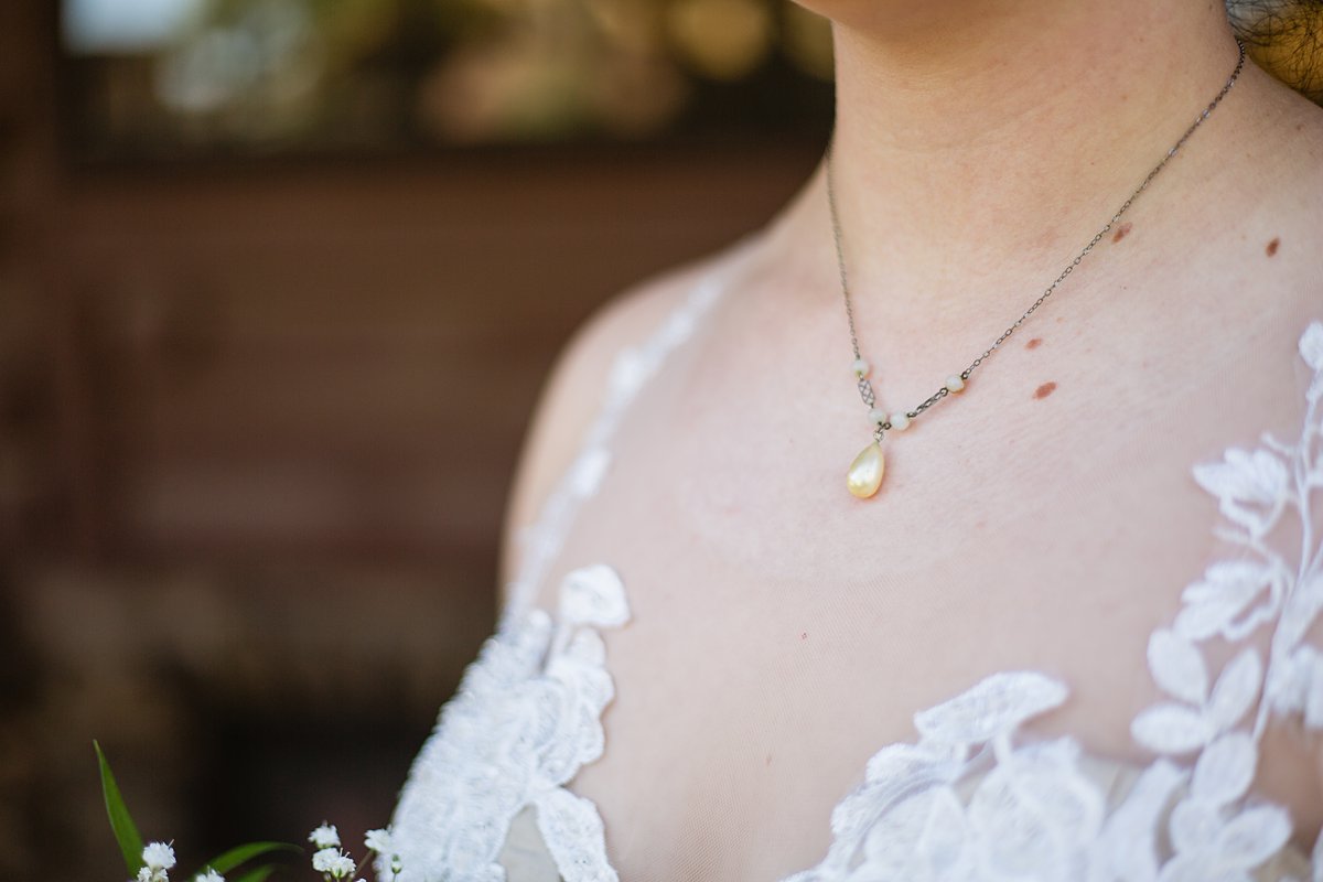 Bride wearing her mother's simple gold necklace on her wedding day by PMA Photography.