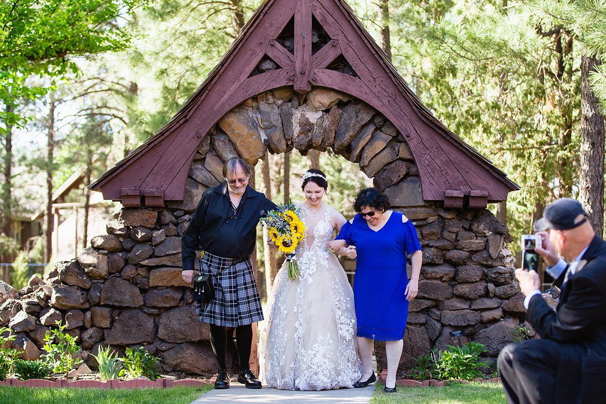 Bride walks down the aisle with her mother and father at her wedding ceremony at the Riordan Mason in Flagstaff , Arizona by PMA Photography.