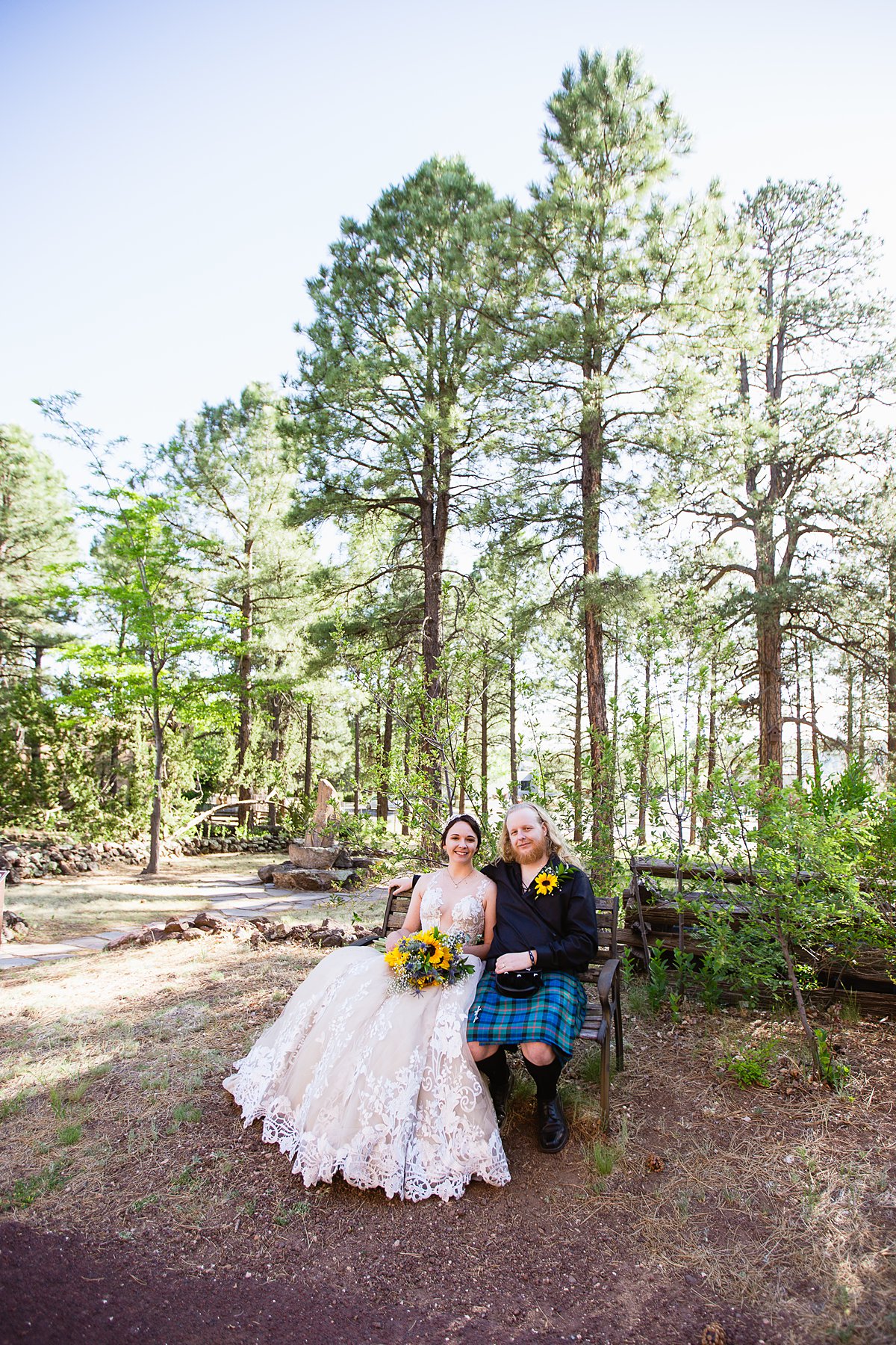 Bride and groom sit on a bench in the woods at the Riordan Mansion at their Scottish and Sunflower inspired wedding by Flagstaff wedding photographers PMA Photography.