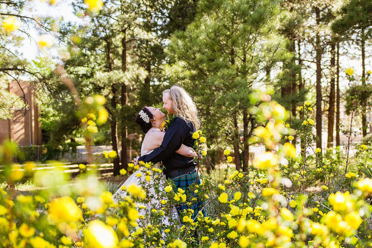 Bride and groom share an intimate moment in front of heirloom yellow roses at the Riordan Mansion by Flagstaff wedding photographers PMA Photography.