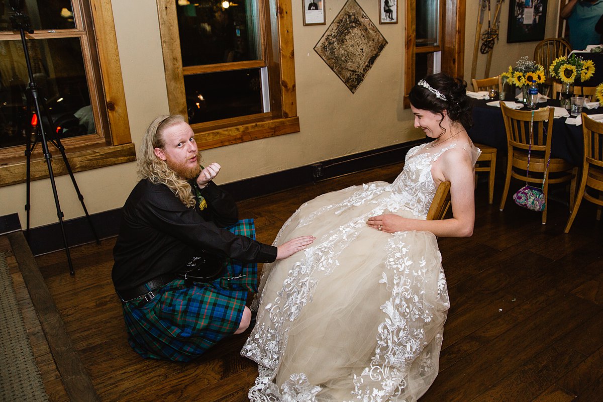 Kilted groom prepares to get his bride's garter at a wedding reception at the Weatherford Hotel in Flagstaff Arizona by wedding photographers PMA Photography.