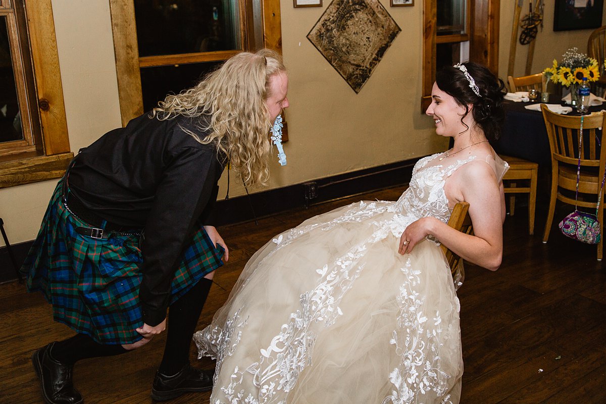 Kilted groom gets the garter at a wedding reception at the Weatherford Hotel in Flagstaff Arizona by wedding photographers PMA Photography.