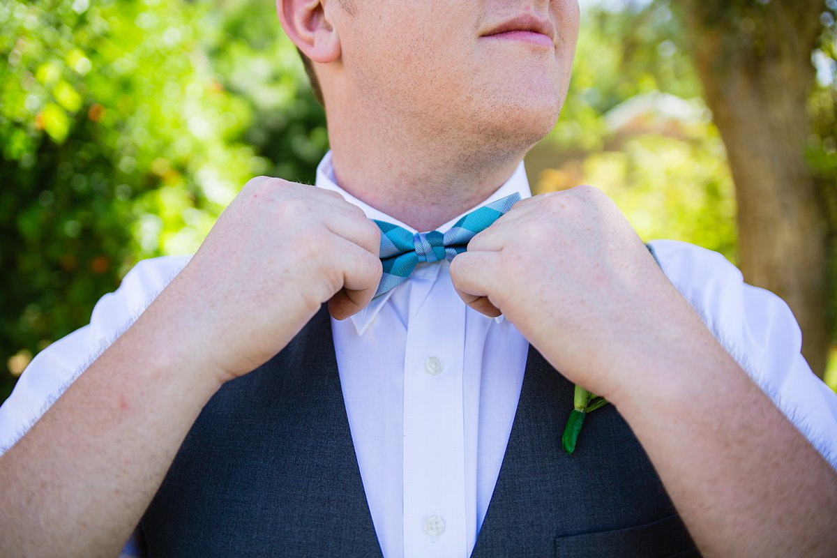 Groom adjusting his bow tie while getting ready for his wedding by PMA Photography.