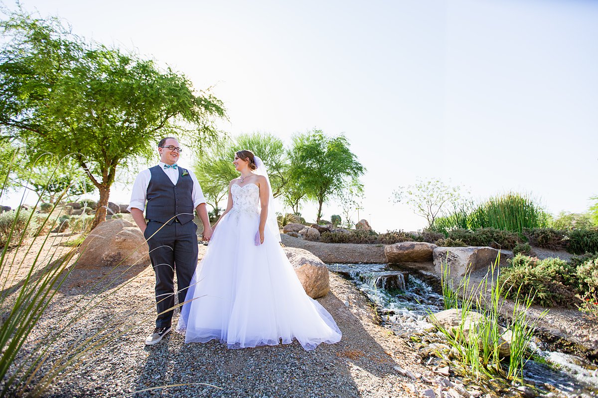 Bride and groom in front of a desert-scaped creek by Arizona wedding photographer PMA Photography.