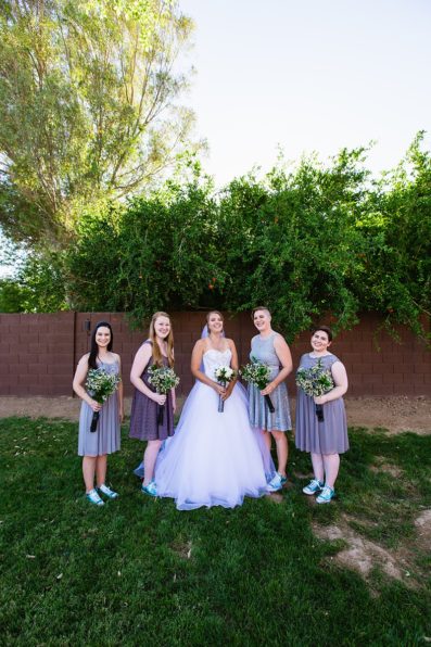 Bride with bridesmaids in grey and turquoise outfits for a DIY backyard wedding by Arizona wedding photographers PMA Photography.