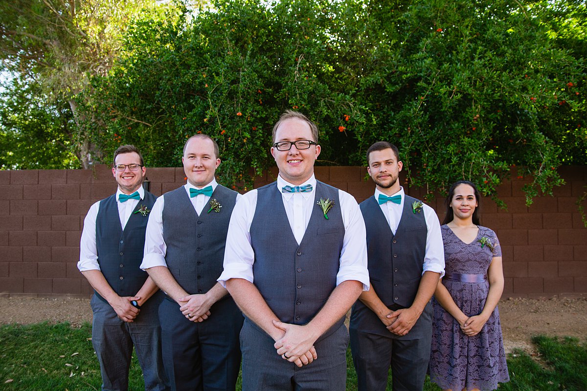 Groom with groomsmen and grooms-lady in grey and turquoise outfits for a DIY backyard wedding by Arizona wedding photographers PMA Photography.