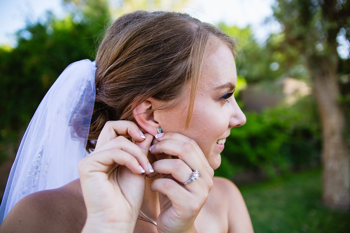 Bride adjusting her blue Disney Mickey Mouse ear rings getting ready for her wedding day by PMA Photography.