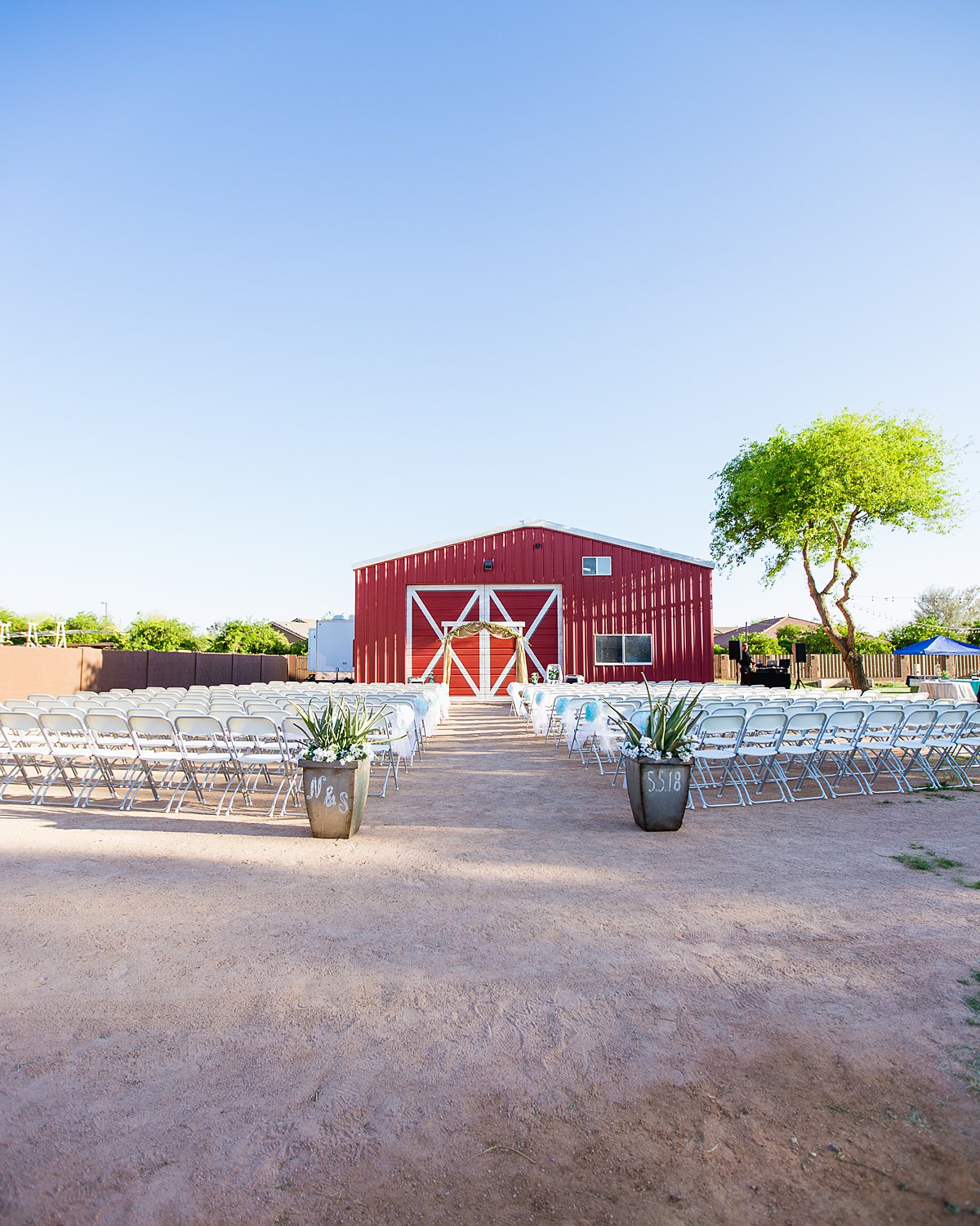 DIY backyard wedding ceremony in front of large red barn by Arizona wedding photographer PMA Photography.