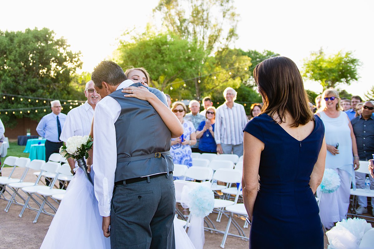 Bride hugging her dad after he walked her down the aisle at a DIY backyard wedding by Phoenix wedding photographers PMA Photography.