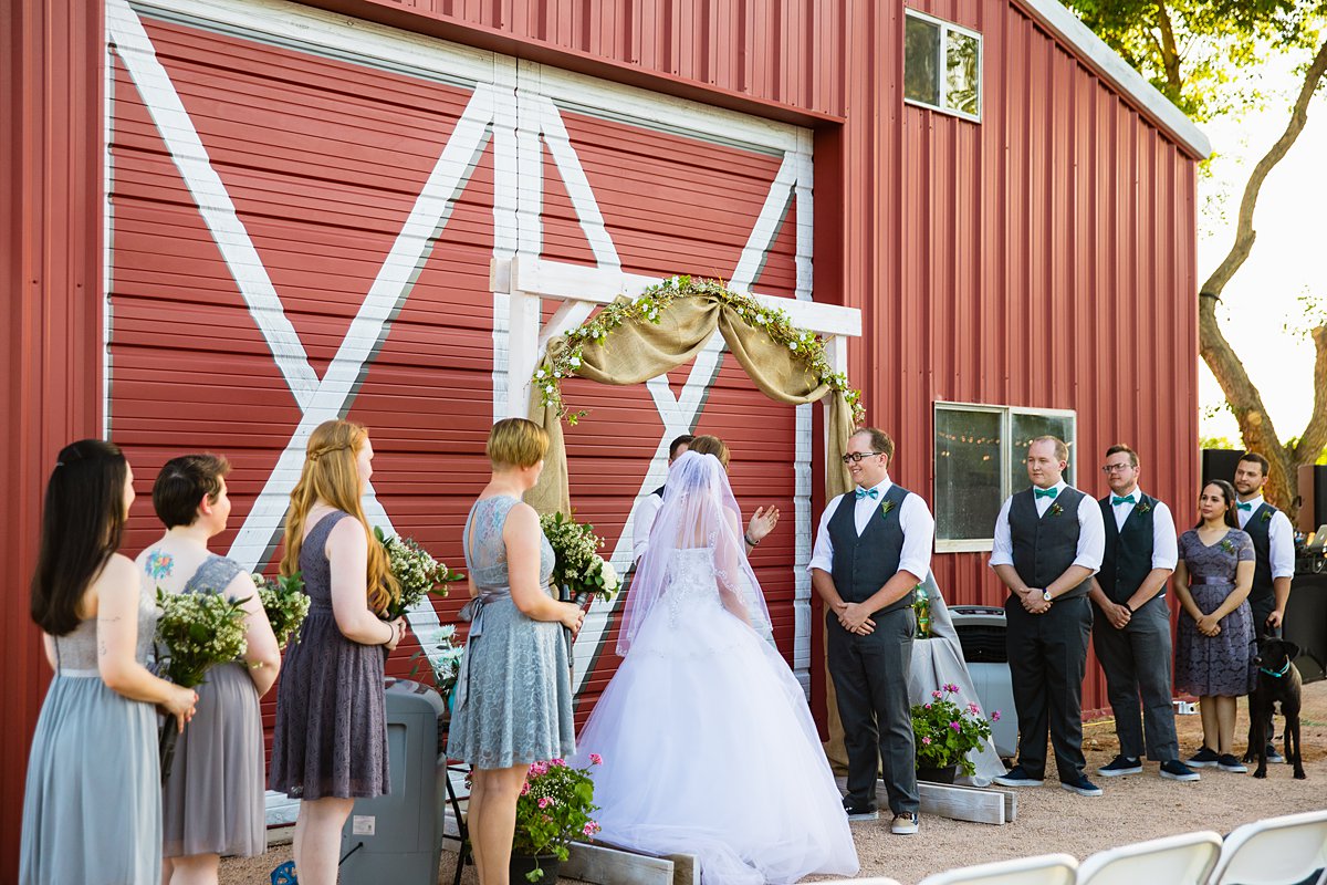 Backyard wedding ceremony in front of red barn by Phoenix wedding photographers PMA Photography.