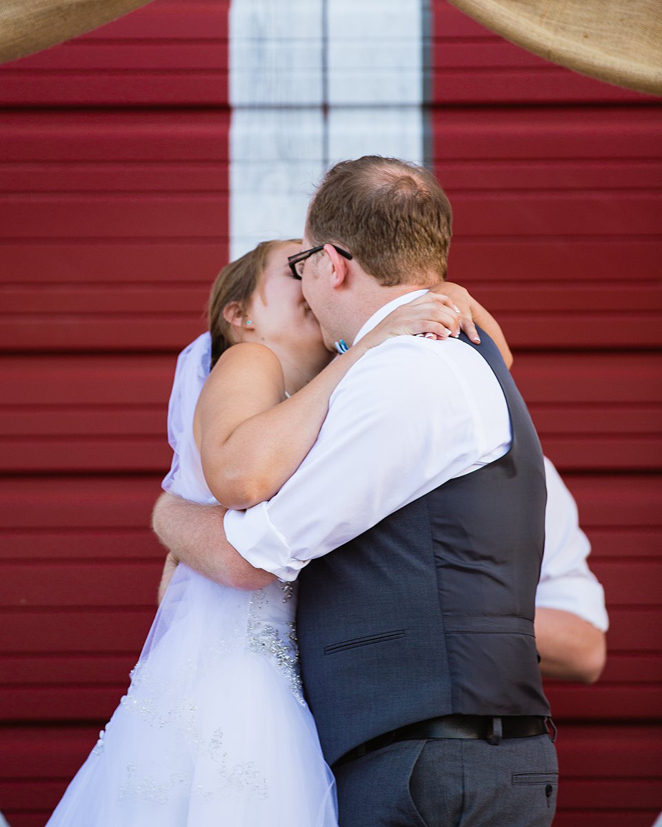 Bride and groom share a their first kiss as husband at wife at their DIY backyard wedding by PMA Photography.