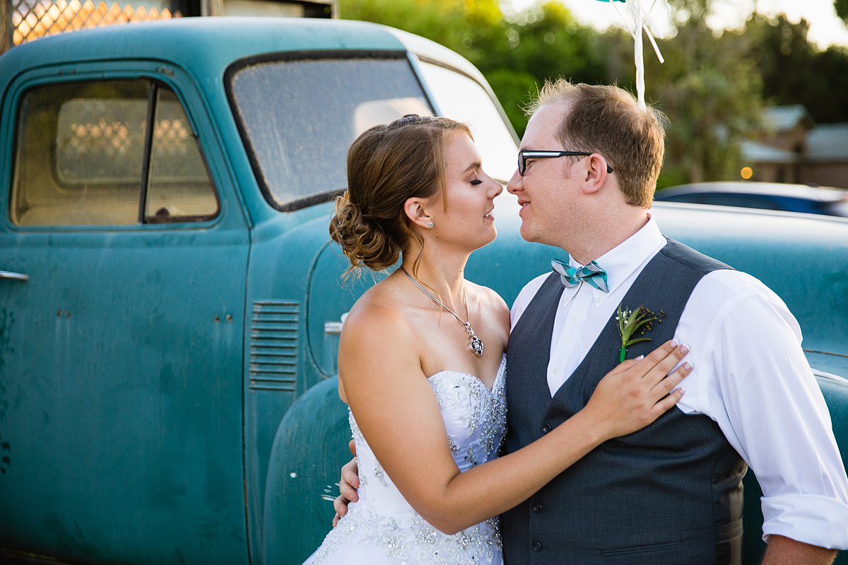Bride and groom share an intimate moment in front of a vintage blue truck by Arizona wedding photographer PMA Photography.