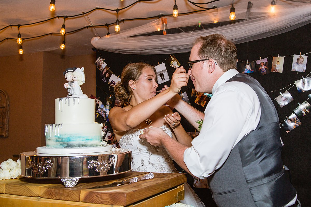 Bride and groom feeding each other wedding cake by PMA Photography.