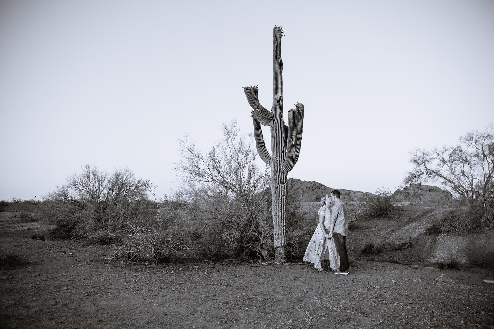 Black and white image of couple with saguaro cactus during their desert engagement session by Arizona engagement photographer PMA Photography.