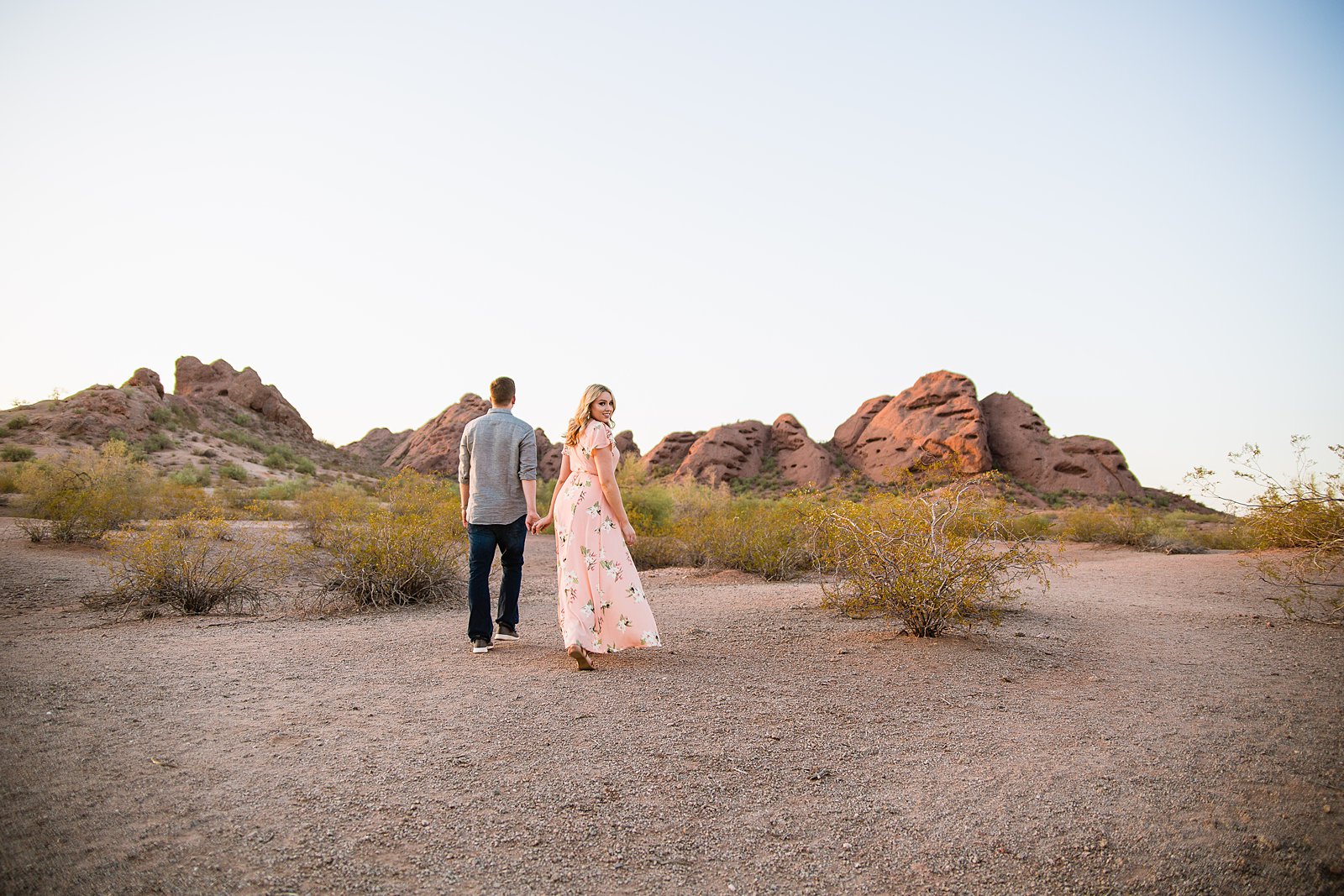 Couple walking through the desert during their Papago Park engagement session by Phoenix engagement photographer PMA Photography.