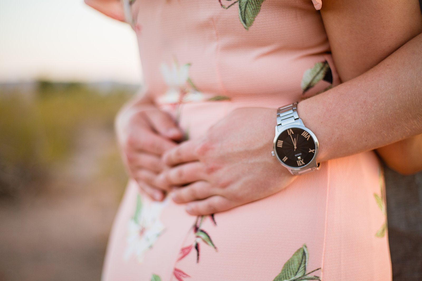 Detail image of groom's watch while holding bride's waist during their engagement session by PMA Photography.