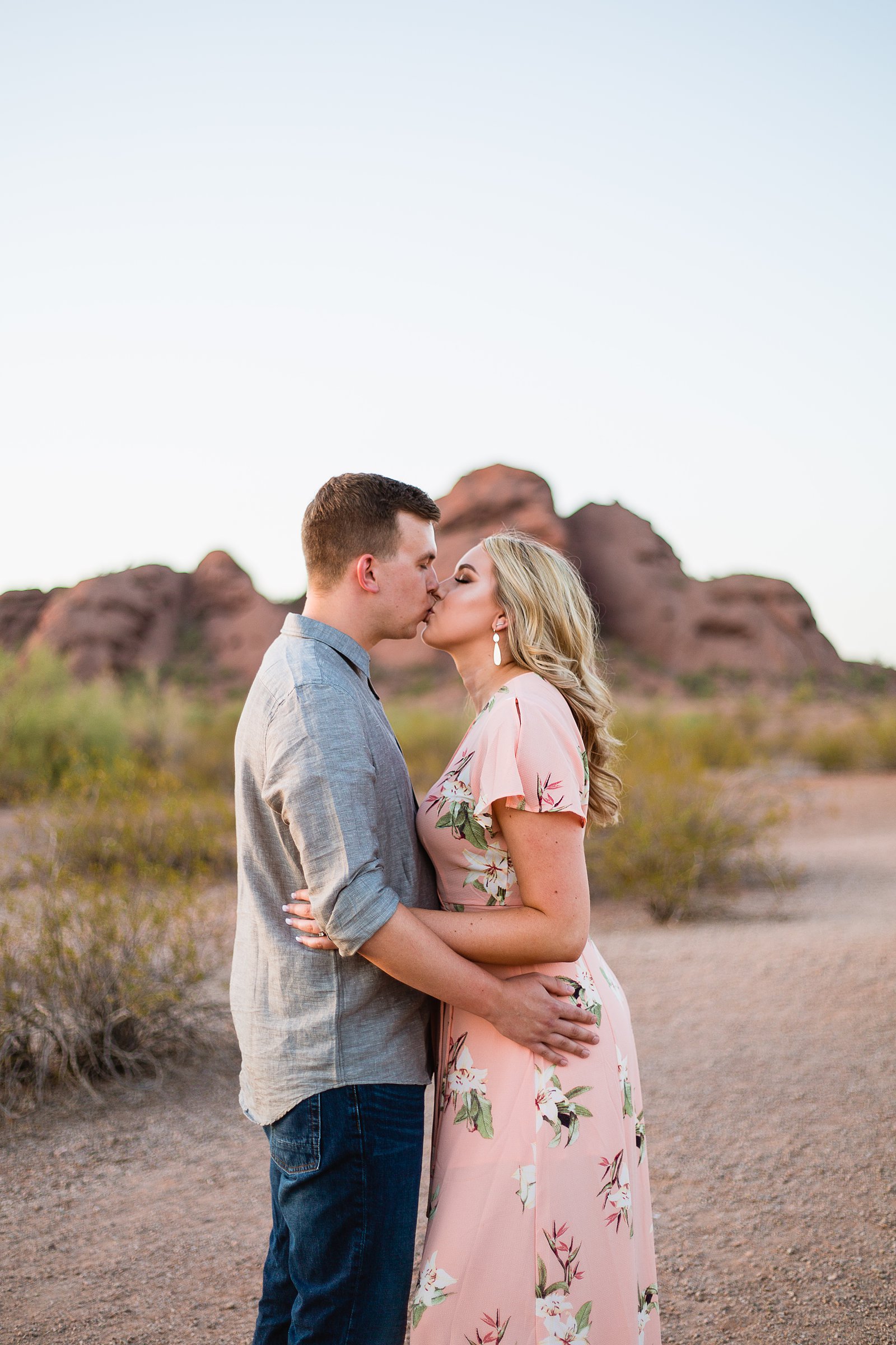 Couple share a kiss during their desert engagement session at Papago Park by Arizona engagement photographer PMA Photography.