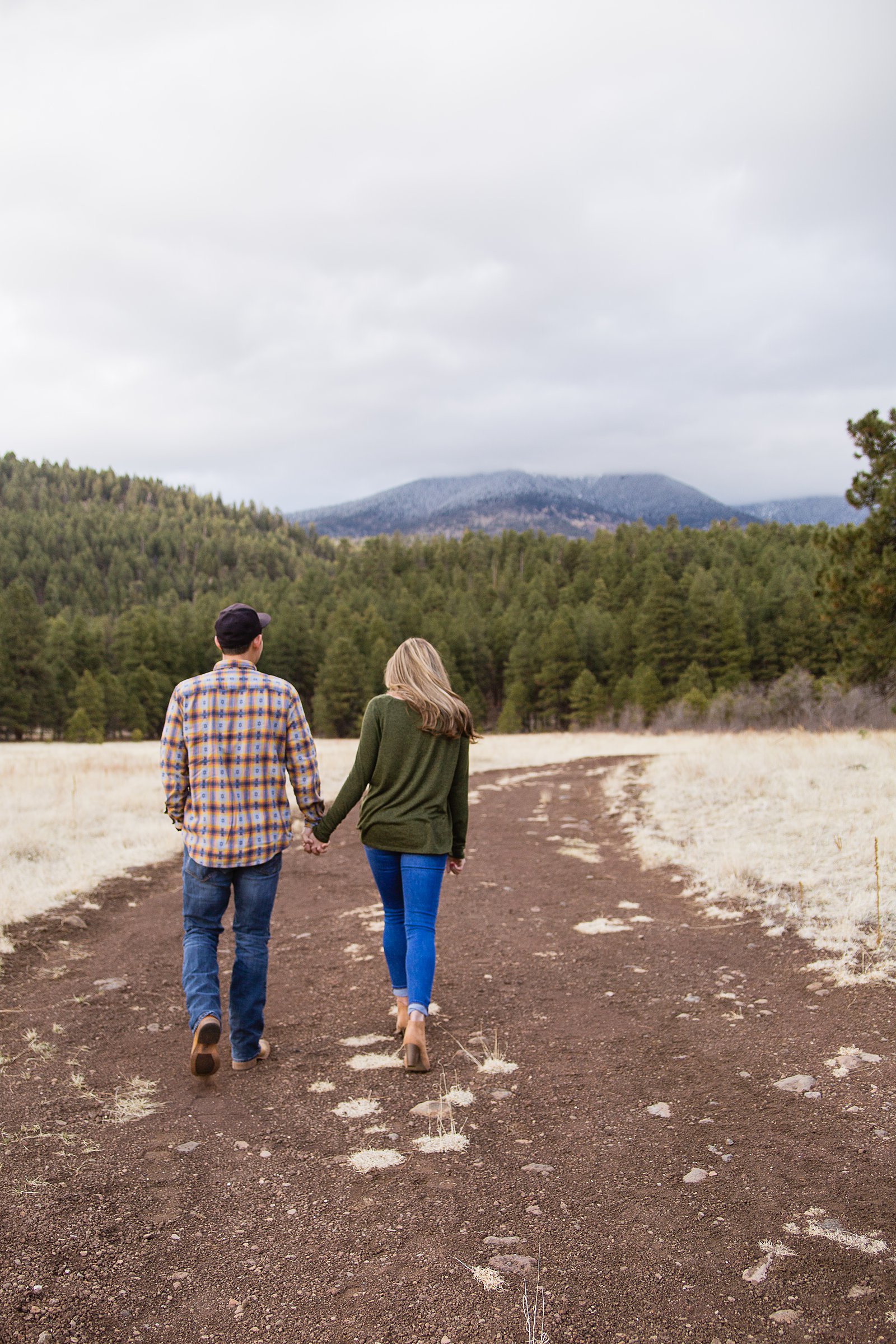Coupling walking down a path holding hands during their Flagstaff engagement session by PMA Photography.
