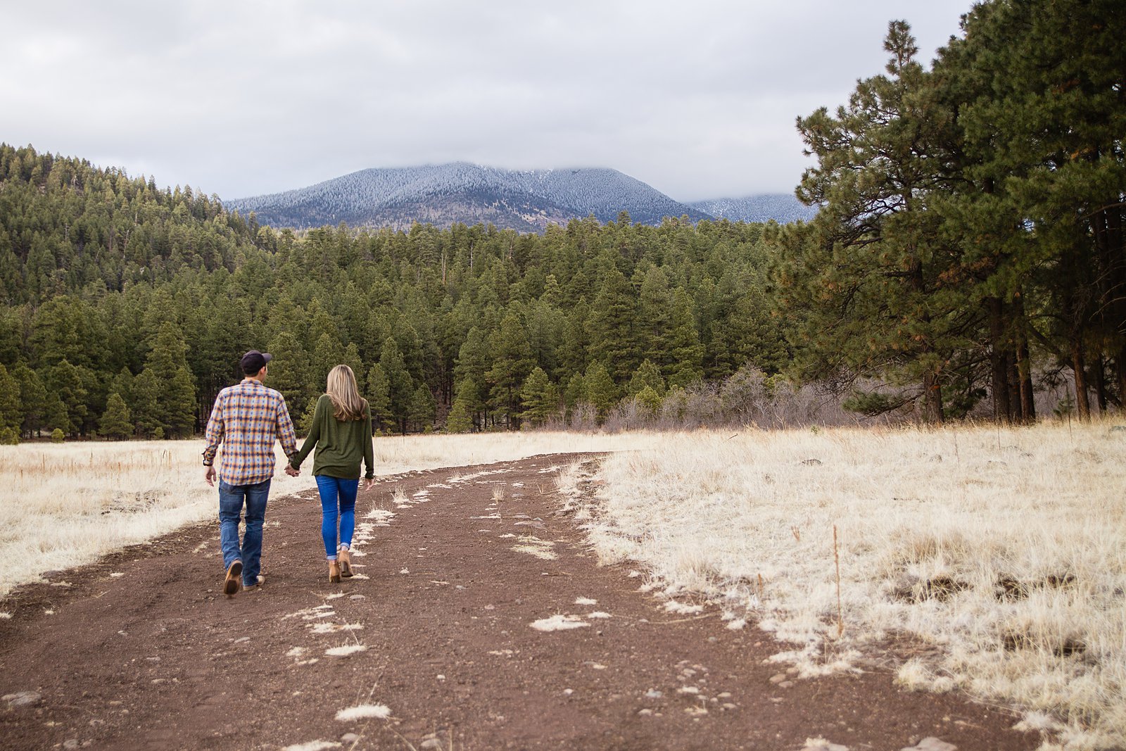 Coupling walking down a path holding hands during their Flagstaff engagement session by PMA Photography.