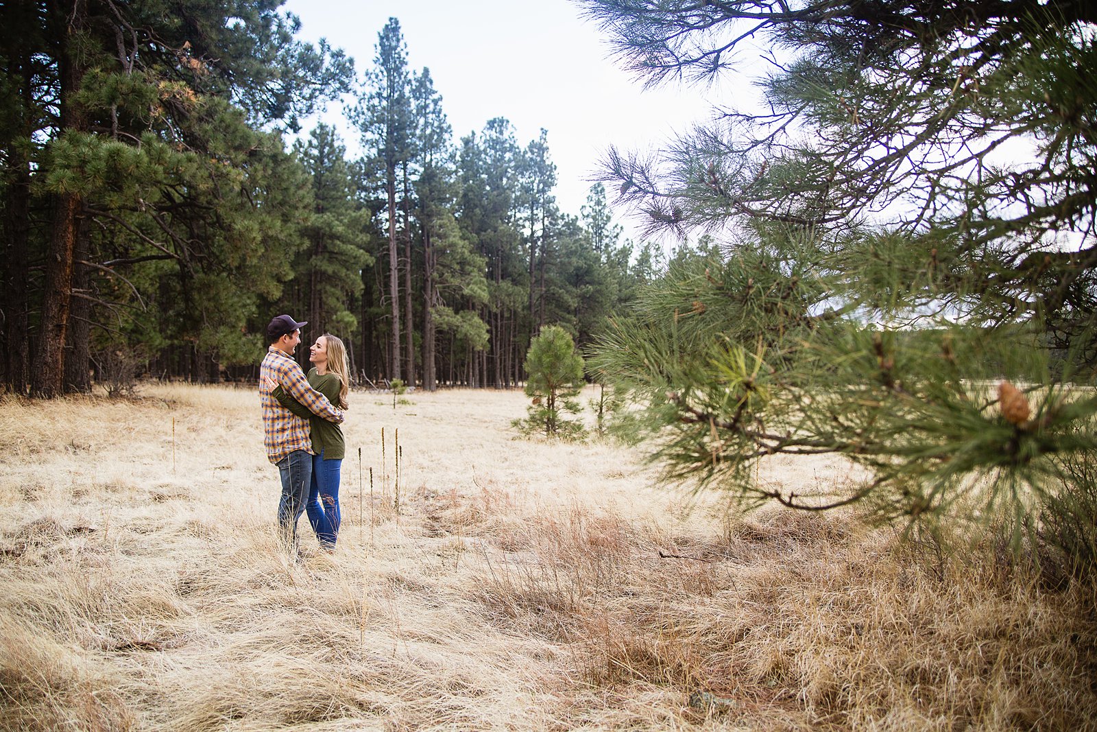Couple look at each other during their Flagstaff engagement session in the woods by PMA Photography.