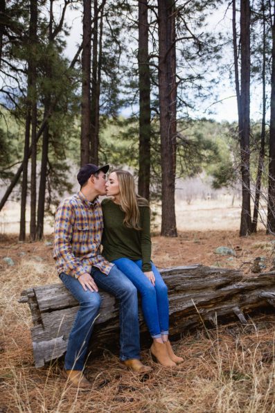 Couple share a kiss in the woods during their Flagstaff engagement session by PMA Photography.