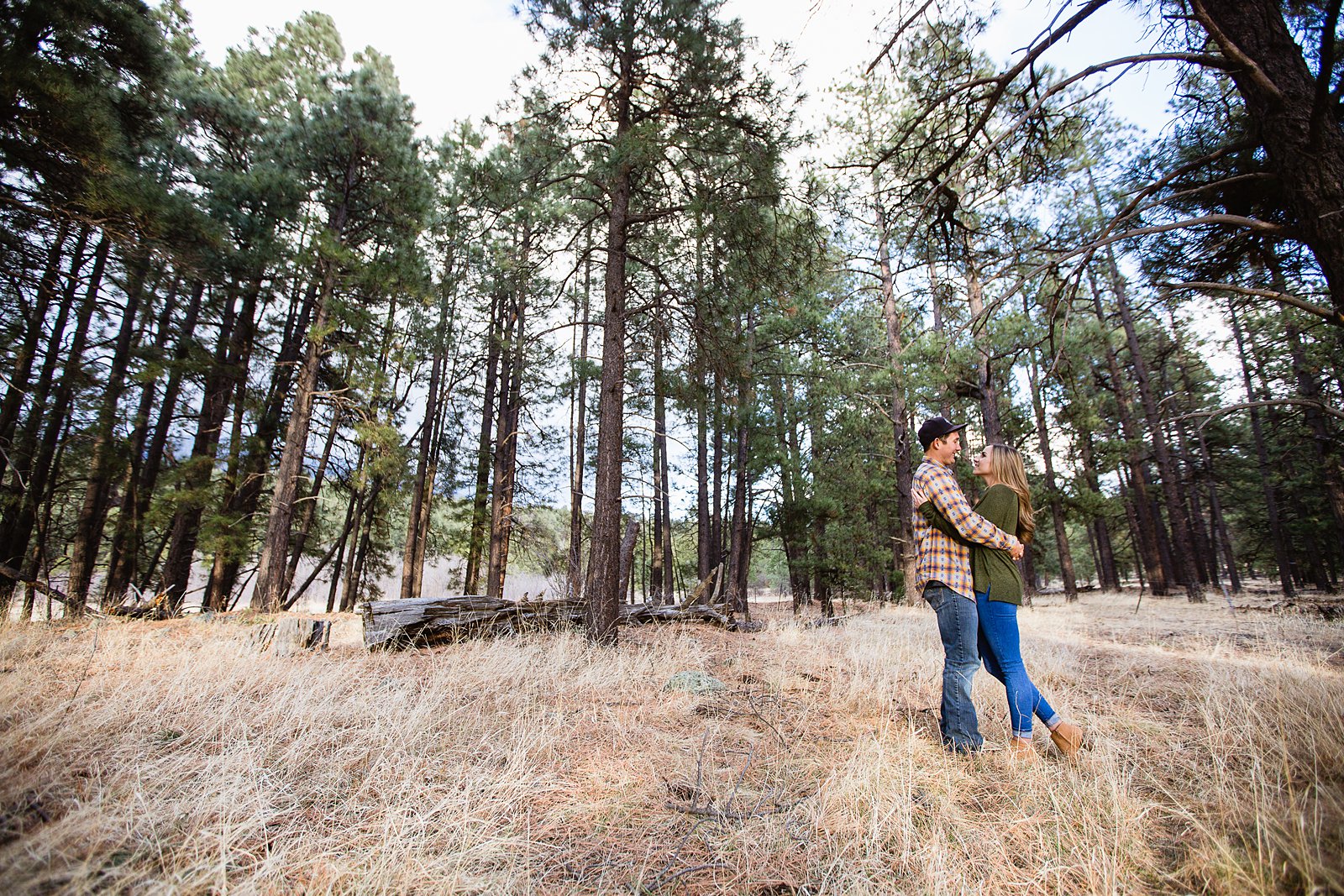 Couple looking at each other in the woods during their Flagstaff engagement session by photographer PMA Photography.