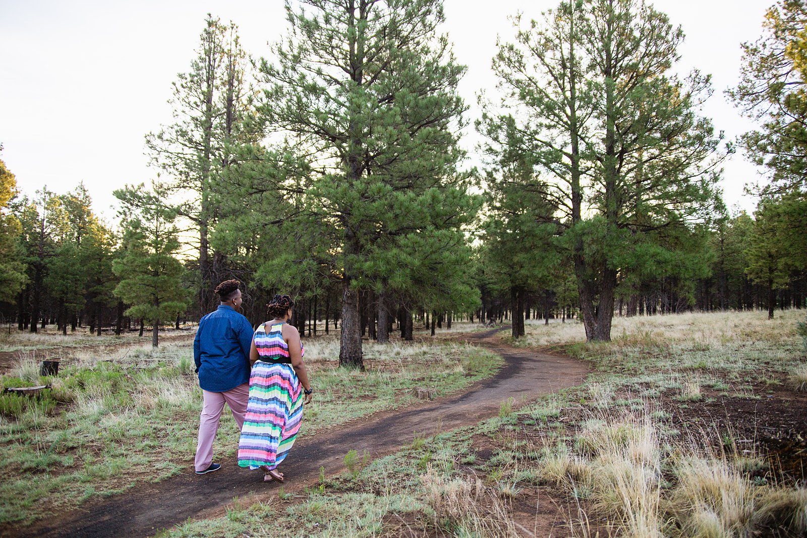 Same sex couple walk through the forest during their Flagstaff engagement session by Arizona engagement photographer PMA Photography.