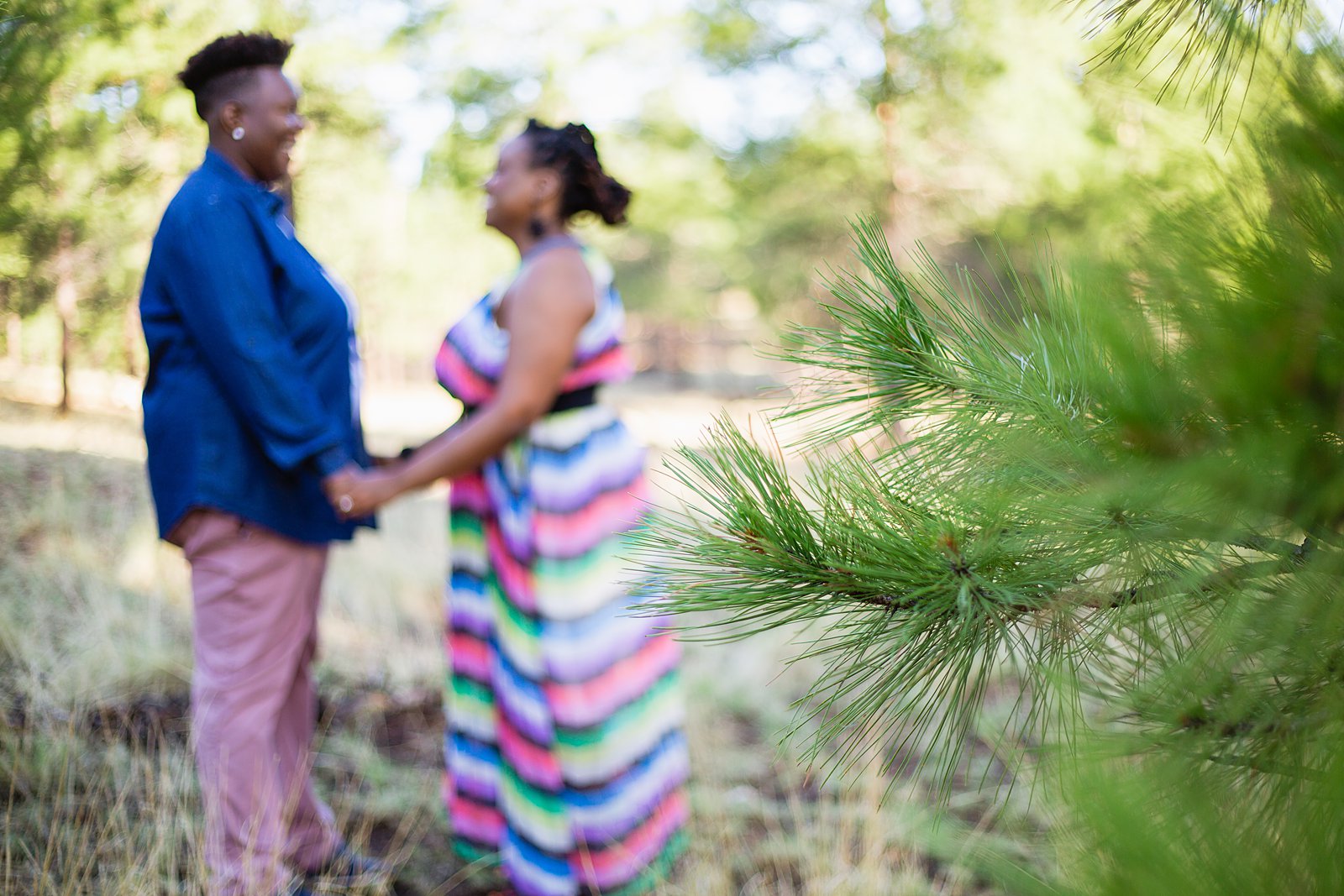 LGBT couple stand behind pine tree during their Flagstaff engagement session by PMA Photography.